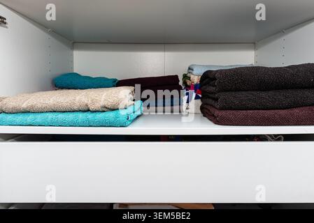 Wardrobe interior showing stacks of neatly folded towels, representing organization and tidiness Stock Photo