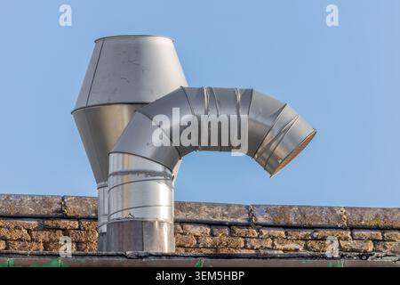 Stainless steel roof-mounted extraction vent used for commercial kitchen ventilation and air handling systems against a clear blue sk Stock Photo
