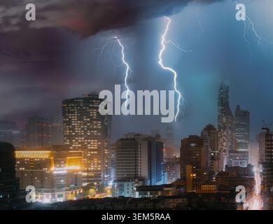 Powerful lightning strikes over modern city skyline at night. Stock Photo