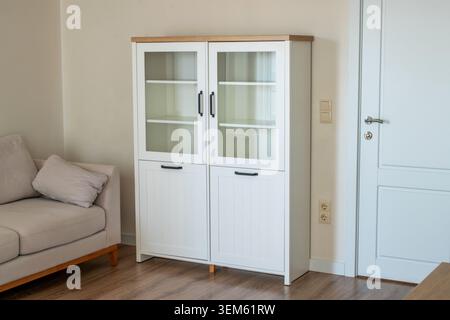 White bookcase with black handles in a room, close-up. Stock Photo