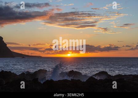 Sun setting over the Atlantic Ocean with dramatic clouds and visible sun rays near the coast of Tenerife, Spain. Stock Photo