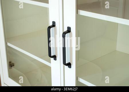 White bookcase with black handles, close-up. Stock Photo