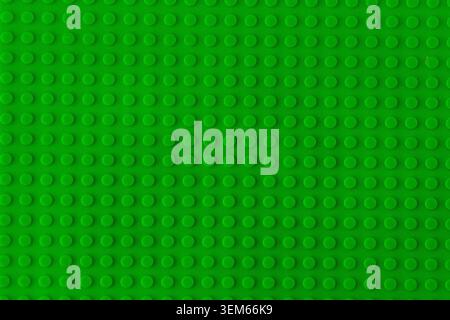 Green plastic building blocks baseplate texture, top view toy brick board pattern background. Round studs for children building blocks Stock Photo