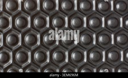 dark black rubber surface with repeating hexagonal honeycomb pattern background texture, raised circular bumps on grip material, full frame macro Stock Photo