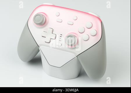 A game controller is placed on a light surface. It shows button layout and ergonomic design elements. Stock Photo