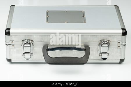 A metal case is placed on a flat surface. The case has a secure handle and metallic locks. It appears to be empty with no visible contents. Stock Photo