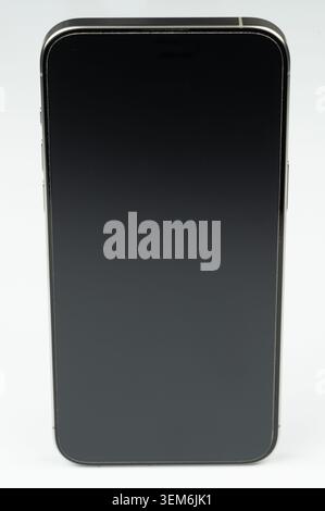 A smartphone is placed on a surface. The screen is off and faces forward. The background is smooth and even. Stock Photo