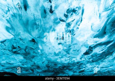 High contrast abstract view of glacial ice cave ceiling in Iceland featuring bold swirling patterns of bright white ice dramatically contrasted agains Stock Photo