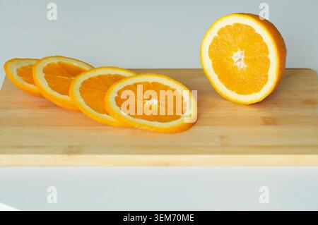 Sliced oranges on a wooden cutting board with white background. Stock Photo