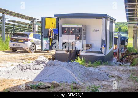 Technician works on an open container with cabling near the car in the solar field, transformer and inverter for 10MW Agri PV system Stock Photo