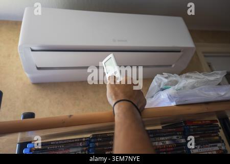 Controlling an air conditioner over a bookshelf with remote control, air-conditioning and refrigeration technology, private house, Wurmberg, Germany Stock Photo