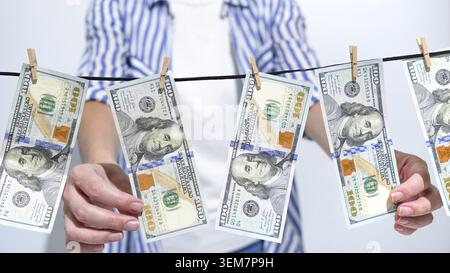 Concept of money laundering with US dollar bills hanging on a clothesline. This image symbolizes financial crime, illegal income, and the process of c Stock Photo