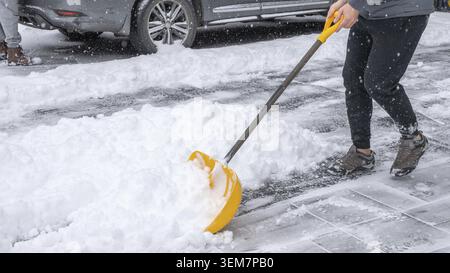 Snow cleaning equipment is being used by an individual to clear a driveway covered in fresh snow, emphasizing winter maintenance and hard work Stock Photo