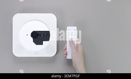 Stylish white portable compact CD player with hand holding controller on grey background. Retro vintage trending disc player. Top view, copy space, sp Stock Photo