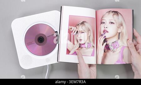 Fan hands holding BlackPink BORN PINK 2nd Album photobook with Rose on grey. Pink music CD in player. South Korean girl group BlackPink. Space for tex Stock Photo