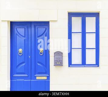 White brick wall with a blue window, door and a grey metal mail box Stock Photo