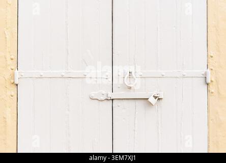 Closed vintage garage gates made of wooden palnks and an iron lock on it painted in beige and ochre colors Stock Photo