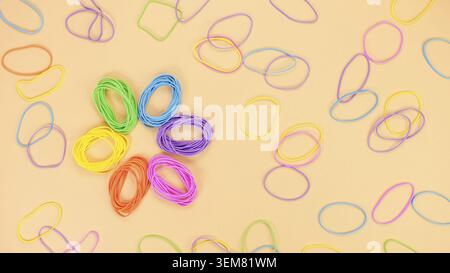 Colored rubber band flower shape on bright yellow paper background. Abstract background. Stationery accessories Stock Photo