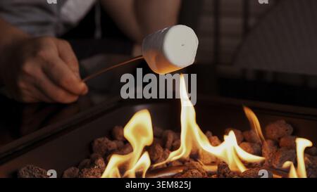 Close up of a marshmallow roasting over an open fire, creating a sweet treat. Enjoying warmth and flavors of summer with friends around the fire pit, Stock Photo