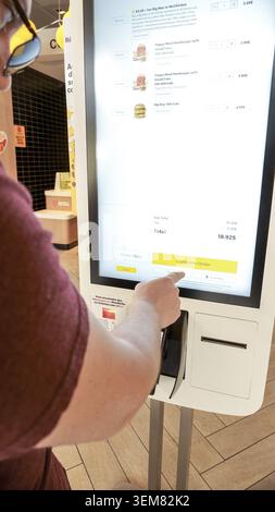 Ottawa ON, Canada - May 15, 2022: Man at McDonald's kiosk is placing an order using touchscreen display in a lively fast-food restaurant setting Stock Photo