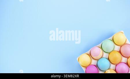 Colorful Easter eggs pack on blue background with space for text. Minimal spring flat lay. Pastel painted eggs in box Stock Photo