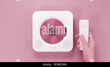 Color of year 2023 Viva Magenta. Image with hand holding controller for stylish portable compact CD player with disc is toned in pantone color. New Fa Stock Photo