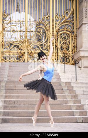 Ballet dancer posing in front of the iconic golden gates of Petit Palais in Paris. Editorial use only due to recognizable architecture. Captured on a Stock Photo