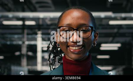 Futureproofing company network, smile close up and pleased female engineer in data center. Increasing cybersecurity,tablet and satisfied cheerful woman portrait in server farm, camera A Stock Photo