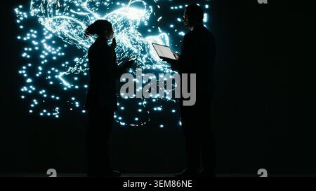 Engineering team optimizes AI machine learning model by adjusting parameters. Tech startup colleagues projecting neural network architecture, brainstorming how to modify datasets, camera B Stock Photo