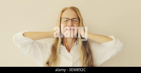 Exhausted tired caucasian mature woman employee with headache, stress, fatigue, temples pain, suffers from migraine, tension in the head in the office Stock Photo