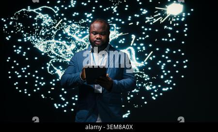 Computer scientist optimizes neural network neurons map with tablet and AR simulation tech. African american man fine tuning machine learning AI model synaptic weights with device, camera A Stock Photo