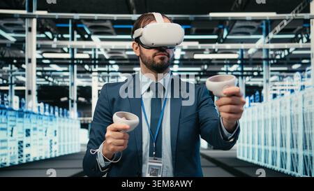 Data center programmer using VR headset tech to do equipment resource optimization. Server farm IT professional using virtual reality simulation to upgrade hardware supercomputers, camera A Stock Photo