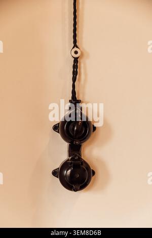 Close up of a vintage bakelite electrical switch and power outlet mounted on a wall with exposed braided cable. Retro industrial interior detail showc Stock Photo