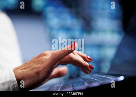 Senescent worker using laptop, setting up high bandwidth dedicated multiplayer gaming servers in high tech workspace to accommodate more traffic from worldwide locations and avoid low ping, close up Stock Photo