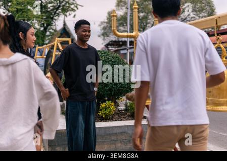Diverse group of young friends interacting outdoors, sharing a happy conversation Stock Photo