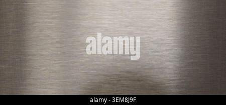 Smooth brushed metal surface with subtle horizontal lines and soft diffused light reflections creating a gradient industrial backdrop Stock Photo