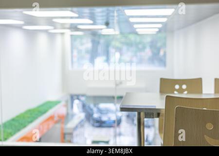 Modern office cafeteria with smiley-face chairs, glass partition, and blurred background view of Stock Photo
