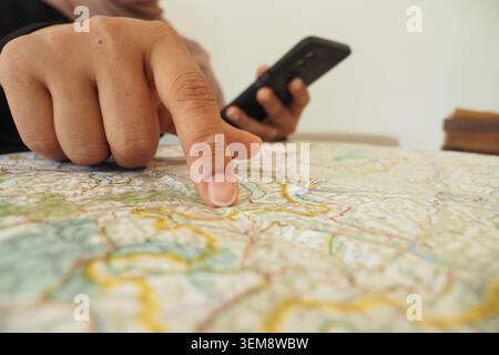 Person studies a map while using a smartphone for directions Stock Photo