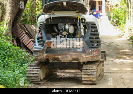 Gritty atmosphere surrounds open engine compartment of dusty industrial excavator vehicle parked on dirt path during construction maintenance work, sh Stock Photo
