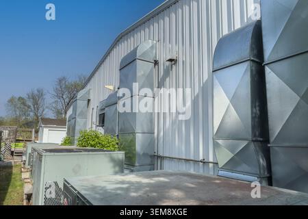 Modern residential air conditioning condenser units installed beside a house with paved walkway and visible utility connections. Stock Photo