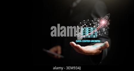 Businessman holding a digital network overlay with data center servers and rocket launch on dark copy space. Growth of cloud infrastructure scaling, t Stock Photo