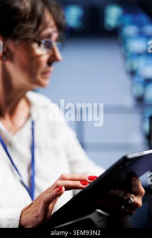 Close up of octogenarian engineer writing script code in data center on laptop terminal. Precise manager doing maintenance work in server room, updating mainframes software to prevent malfunctions Stock Photo