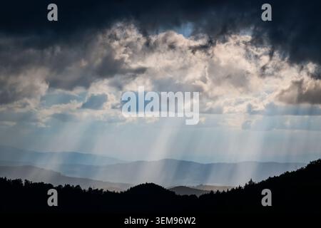 Dramatic crepuscular rays breaking through storm clouds over mountain landscape seen from Kralova skala in Mala Fatra National Park, Slovakia. Stock Photo