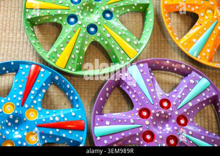 Closeup view of four colorful plastic wheels with raised studs on a woven mat background, showcasing vivid greens, blues, purples, and oranges with pl Stock Photo