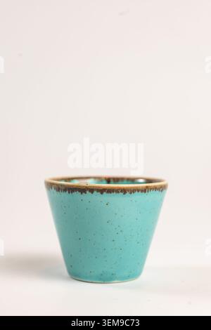 A beautiful handmade-style turquoise ceramic cup with attractive dark speckles and a contrasting rustic brown rim. Photographed in a clean minimalist Stock Photo