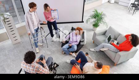 inclusive business presentation with diverse disabled coworkers in modern office, teamwork meeting, accessibility and workplace inclusion concept Stock Photo