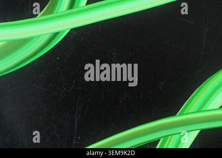 Abstract dark grainy background framed by glowing 3d green tubes Stock Photo