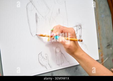 Artist hand drawing human mannequin figure with pencil on white blank canvas in bright natural lighting background. Focus on creative sketching and de Stock Photo