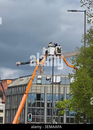 Street Lamp Installation with Hydraulic Lift – A maintenance worker operates an aerial work platform to install a new street lamp in the city. The sce Stock Photo