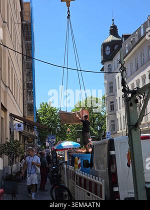 Construction Worker Emptying Debris into Truck – A construction worker carefully guides a hanging bucket of debris from a building site, directing it Stock Photo
